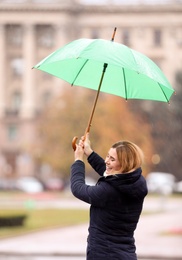 Woman with umbrella in city on autumn rainy day