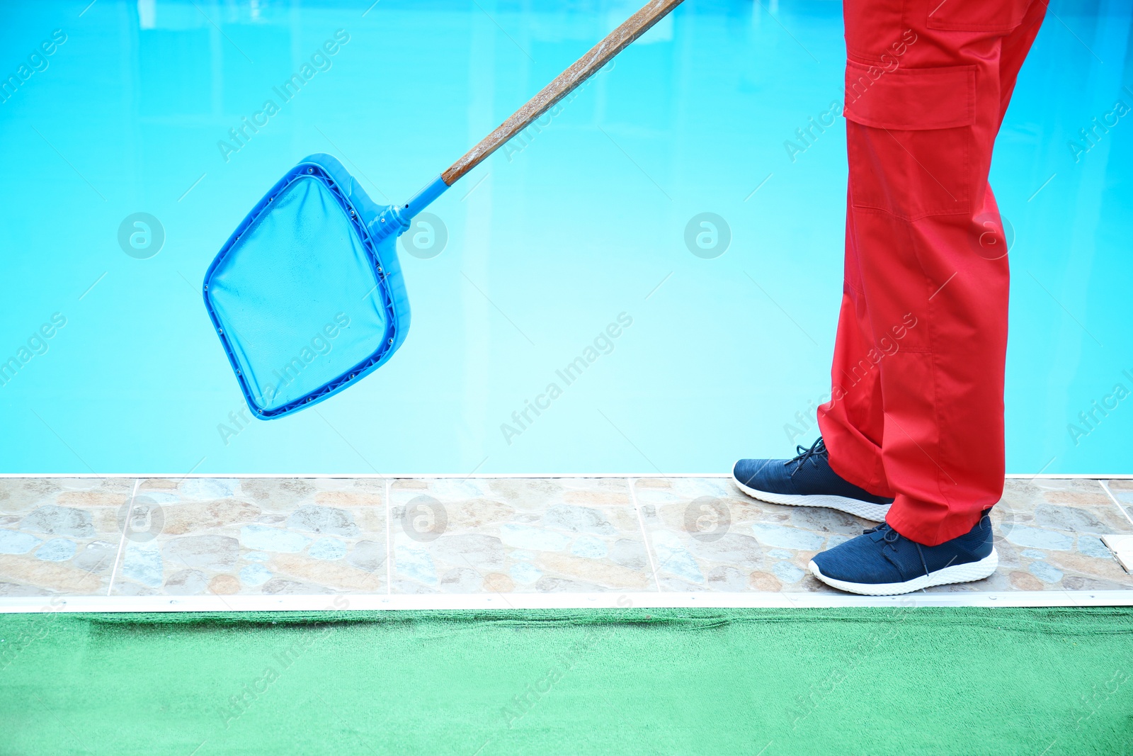 Photo of Male worker cleaning outdoor pool with scoop net