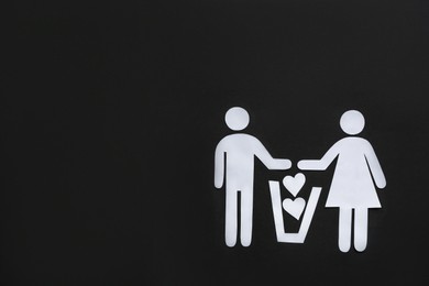 Photo of Divorce concept. Paper cutouts of couple, trash can and hearts on black background, flat lay with space for text