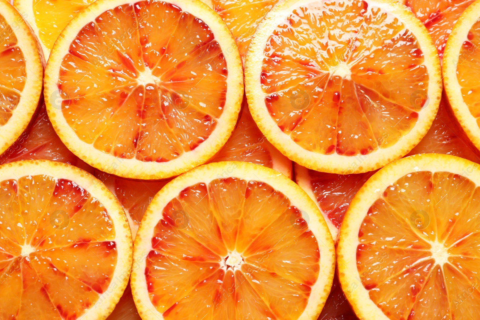 Photo of Juicy blood orange slices as background, top view. Citrus fruit