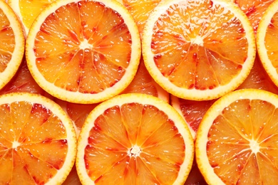 Photo of Juicy blood orange slices as background, top view. Citrus fruit