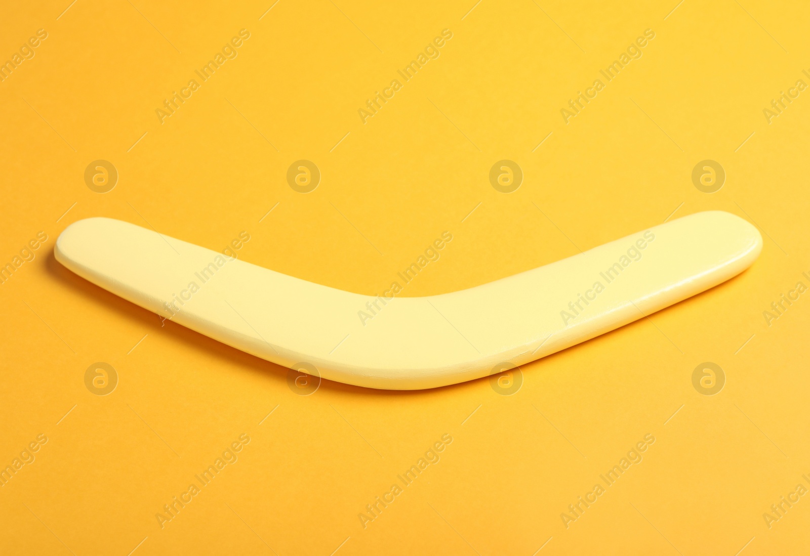 Photo of Wooden boomerang on yellow background. Outdoor activity