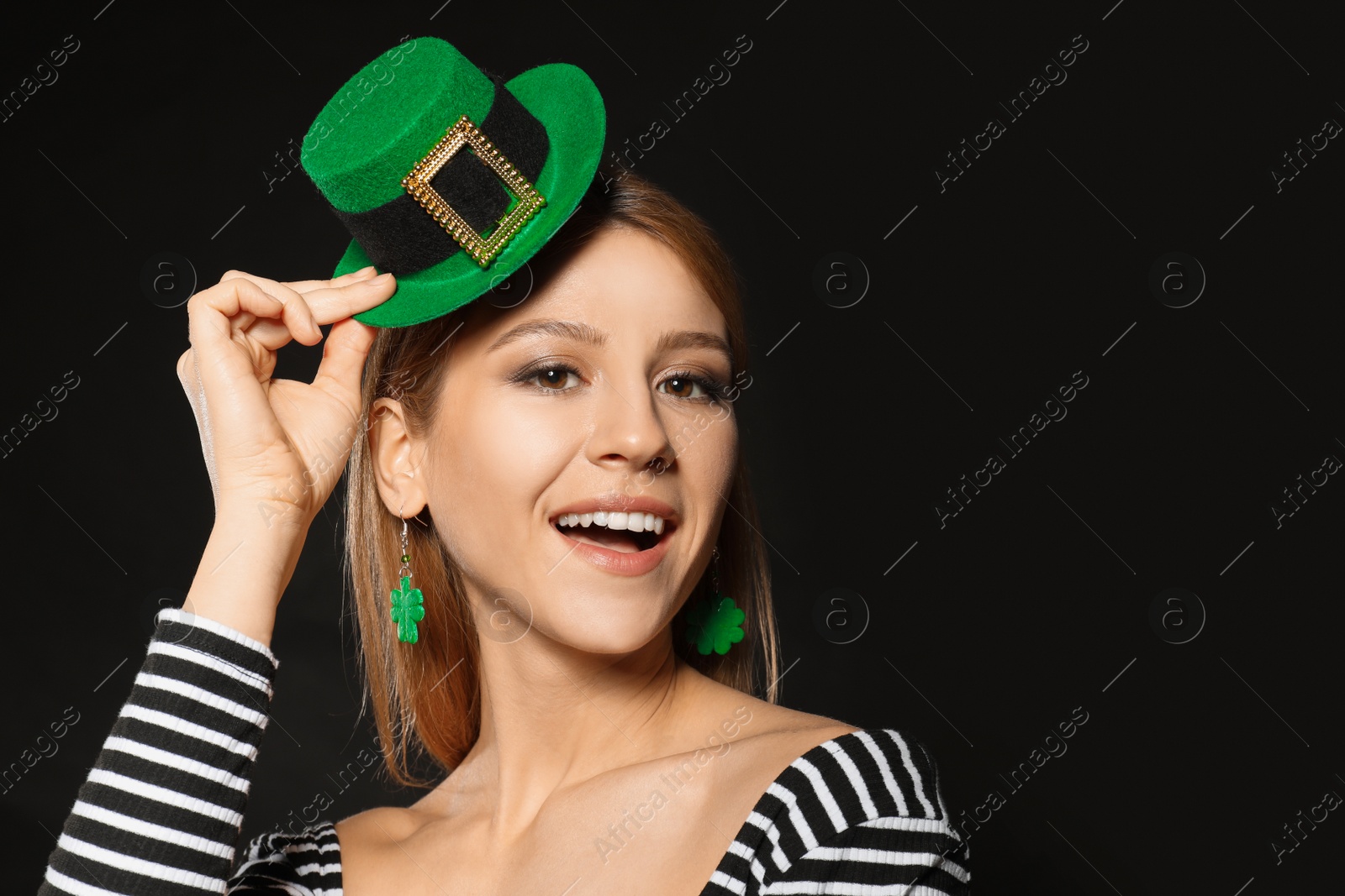 Photo of Young woman with green leprechaun hat on black background, space for text. St. Patrick's Day celebration