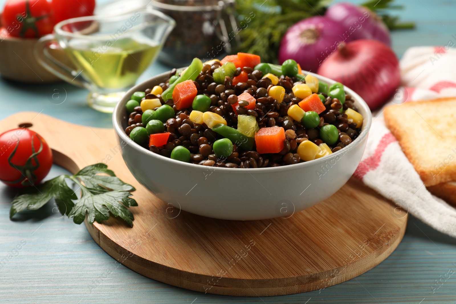 Photo of Delicious lentils with vegetables on light blue wooden table, closeup