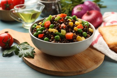 Delicious lentils with vegetables on light blue wooden table, closeup