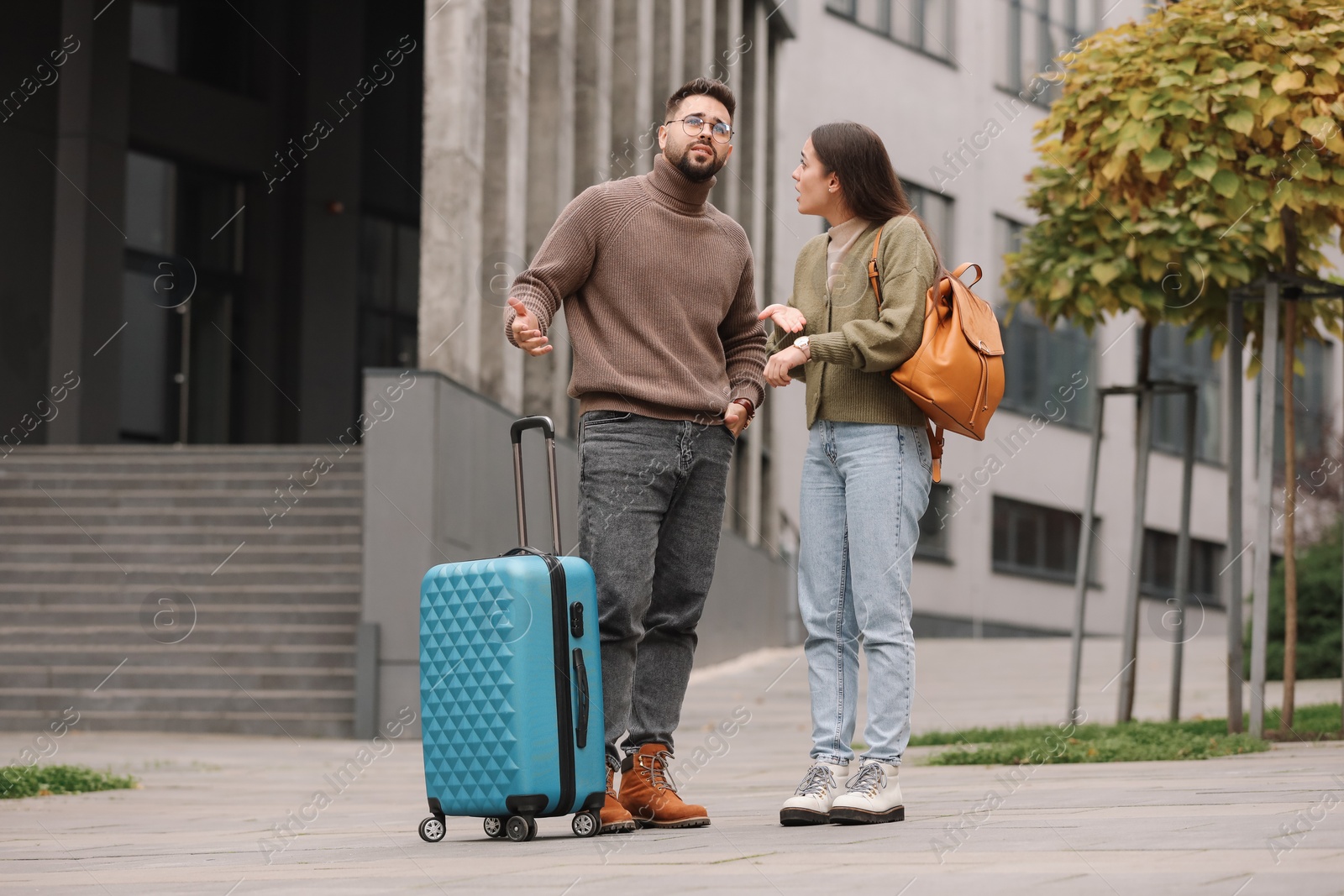 Photo of Being late. Worried couple near building outdoors