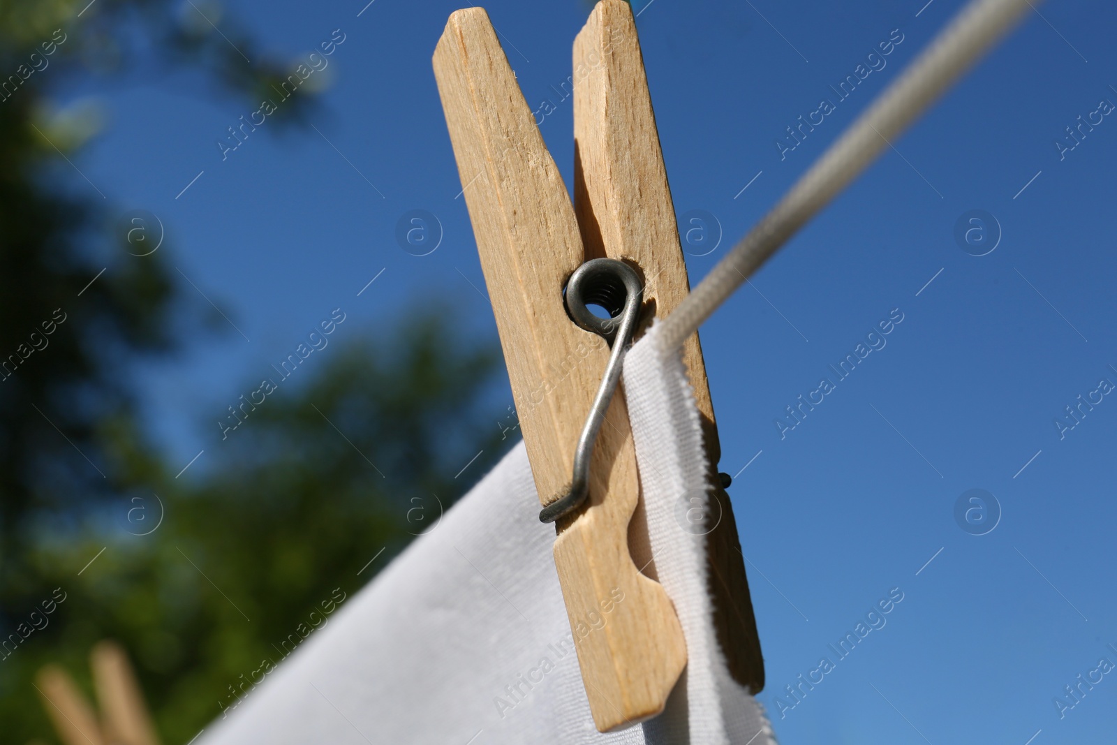 Photo of Washing line with clean laundry and clothespin outdoors, closeup