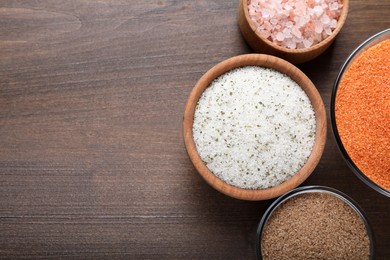 Different kinds of salt on wooden table, flat lay. Space for text