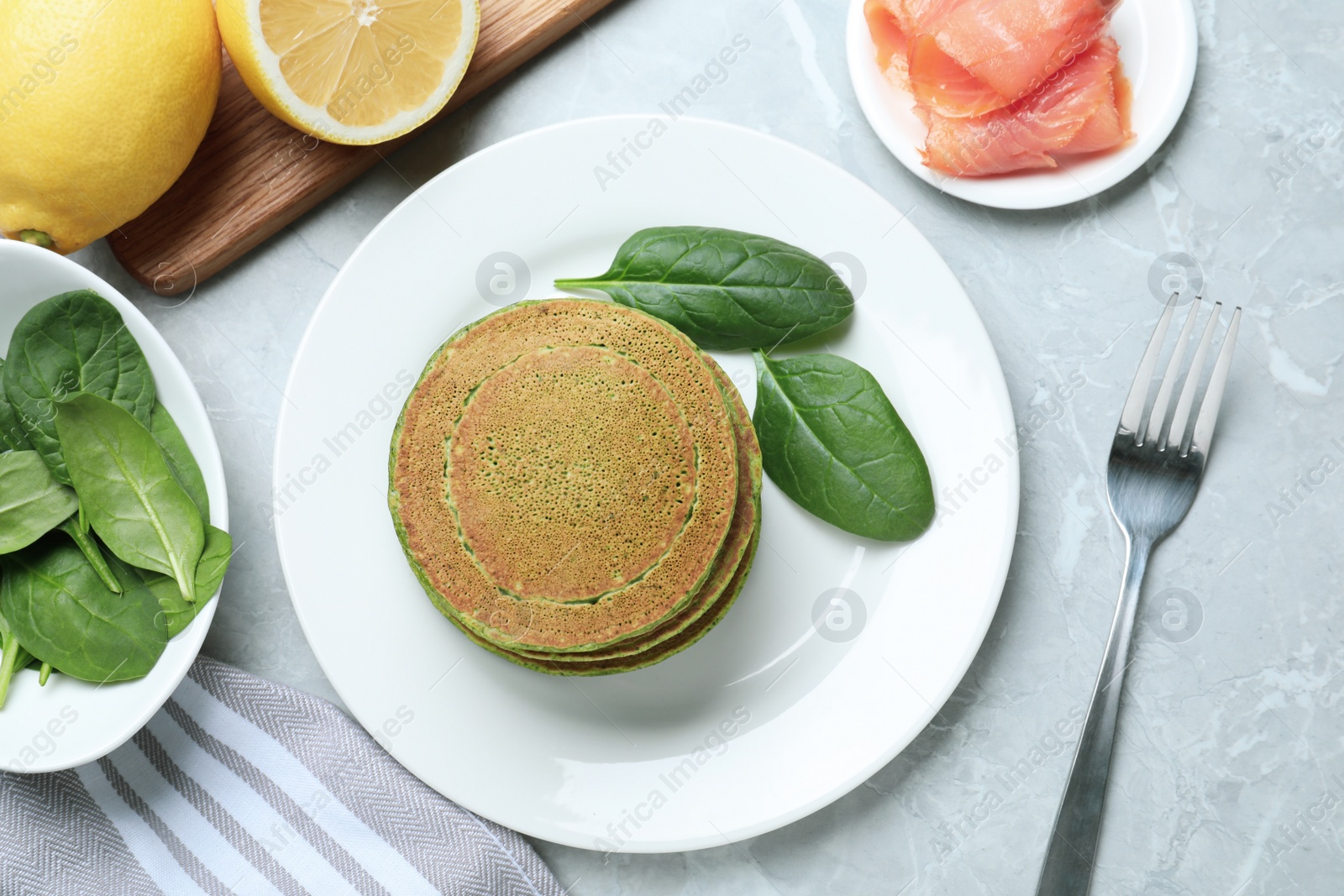 Photo of Tasty spinach pancakes served on light grey marble table, flat lay