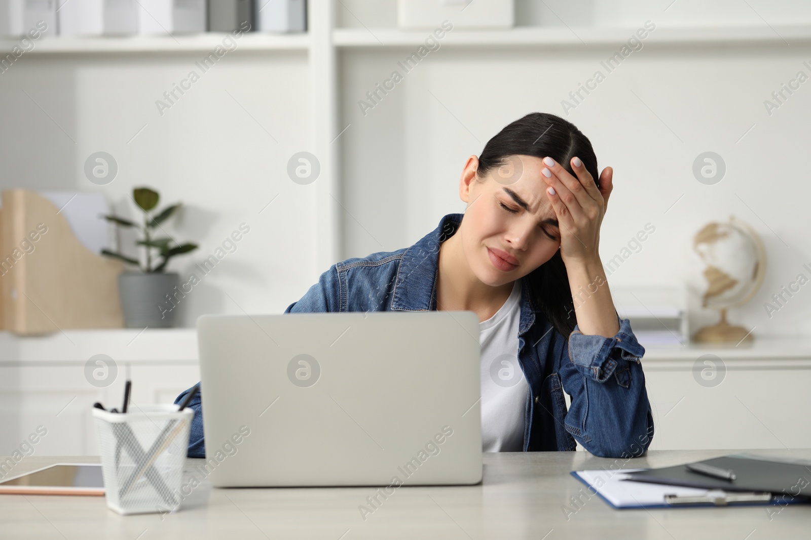 Photo of Woman suffering from headache at workplace in office