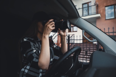 Private detective with camera spying from car