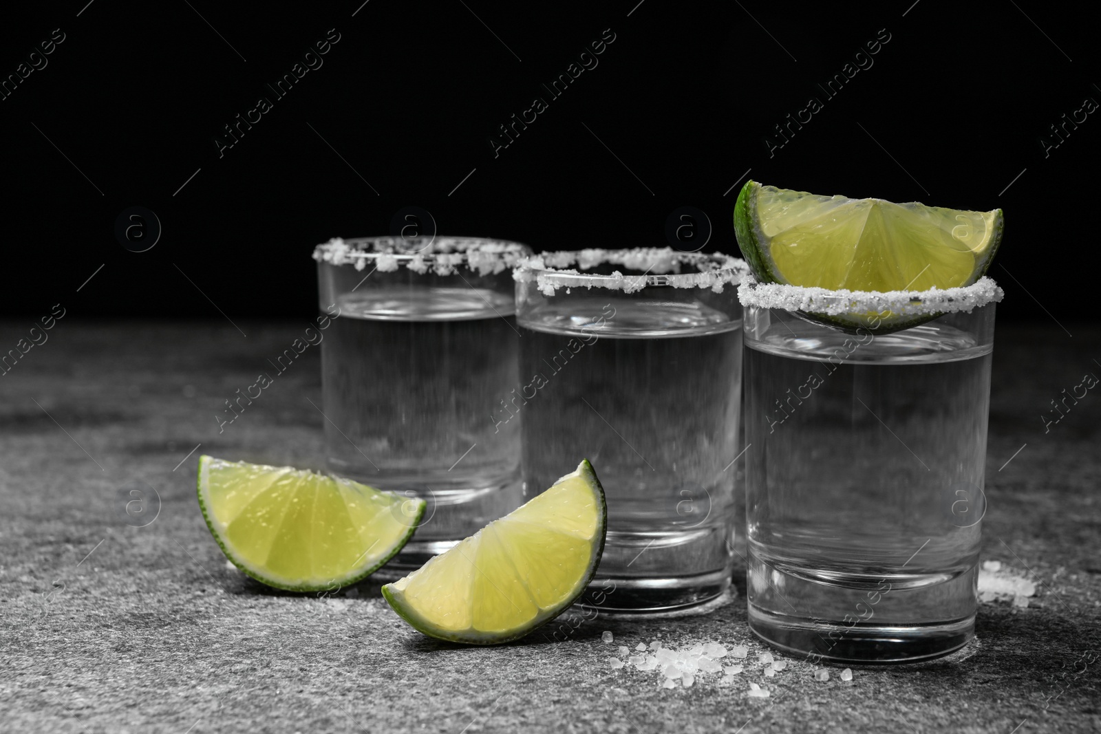 Photo of Mexican Tequila shots with salt and lime slices on grey table