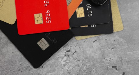 Photo of Pile of different credit cards on grey table, closeup