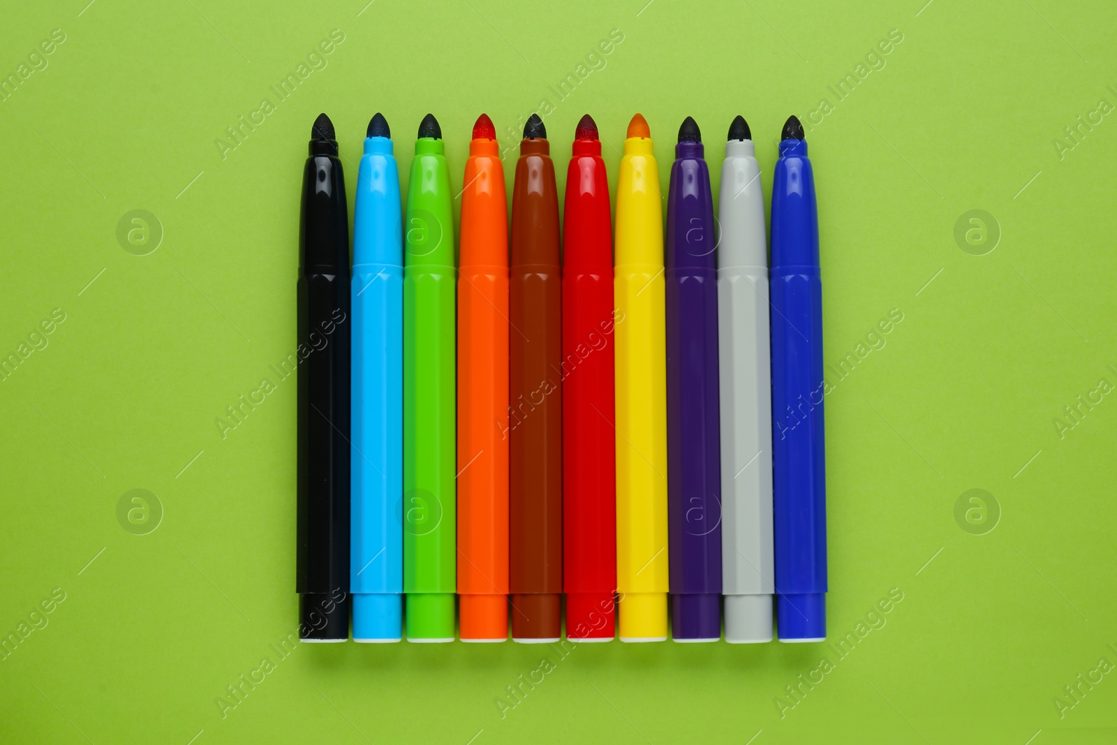 Photo of Many different colorful markers on light green background, flat lay