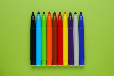 Photo of Many different colorful markers on light green background, flat lay