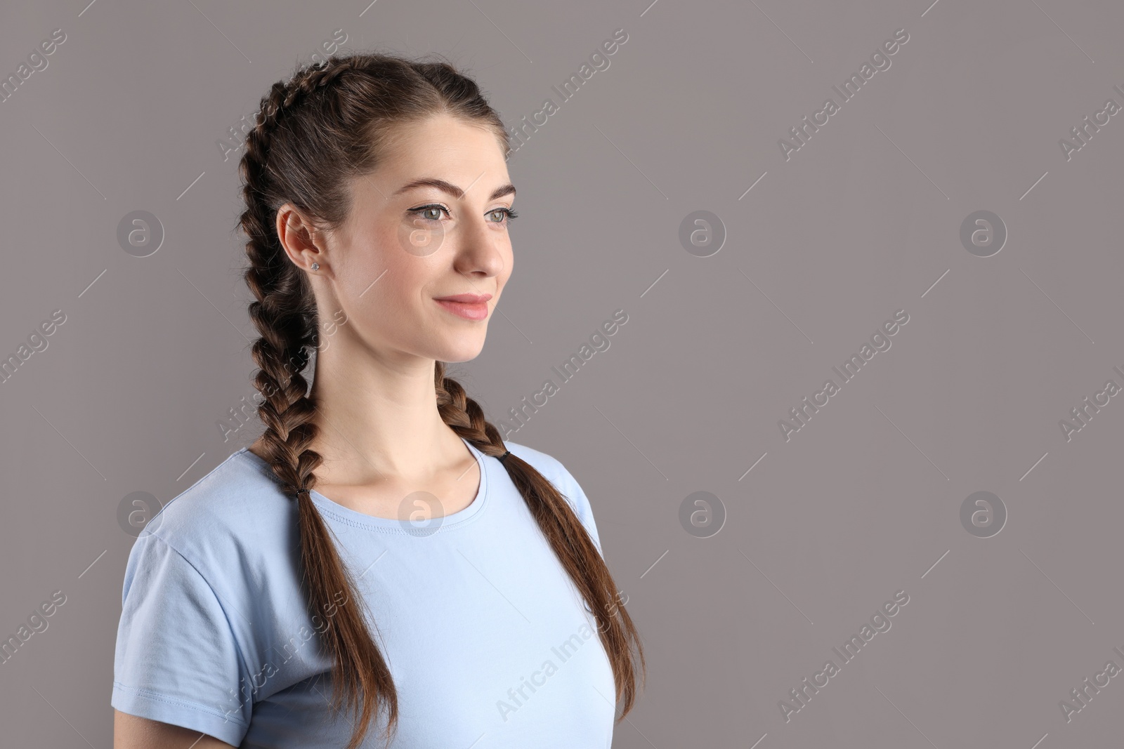 Photo of Woman with braided hair on grey background. Space for text