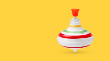 One spinning top in motion on yellow background, banner design with space for text. Toy whirligig