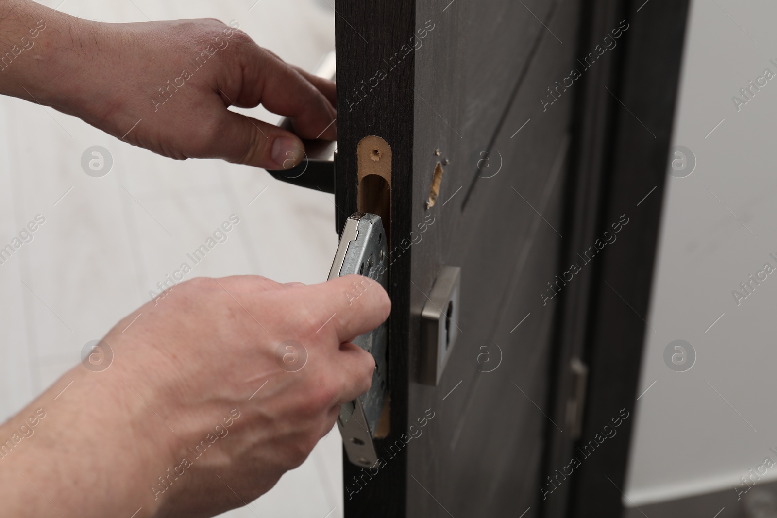 Photo of Handyman changing door handleset indoors, closeup view