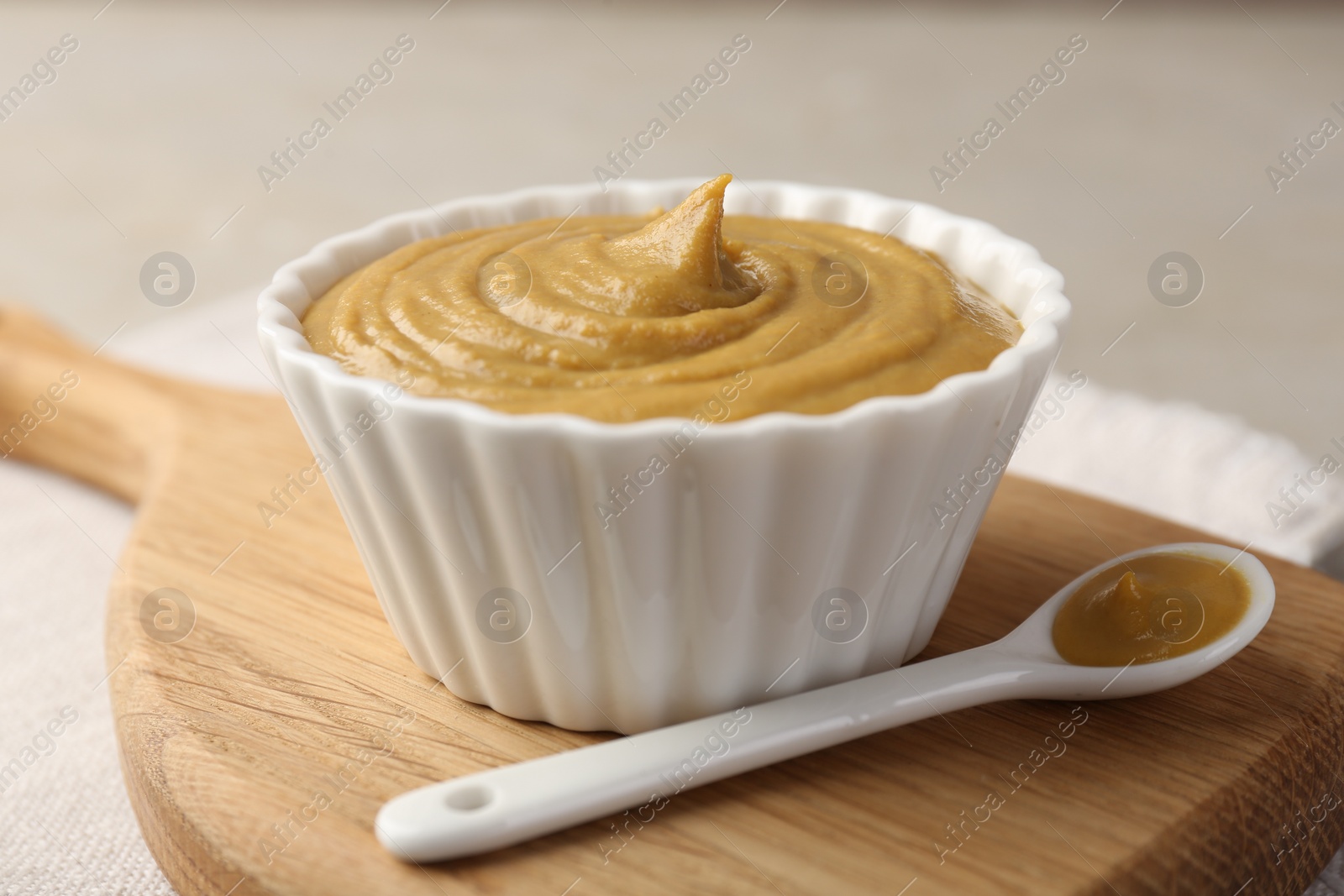 Photo of Bowl and spoon with tasty mustard sauce on light table