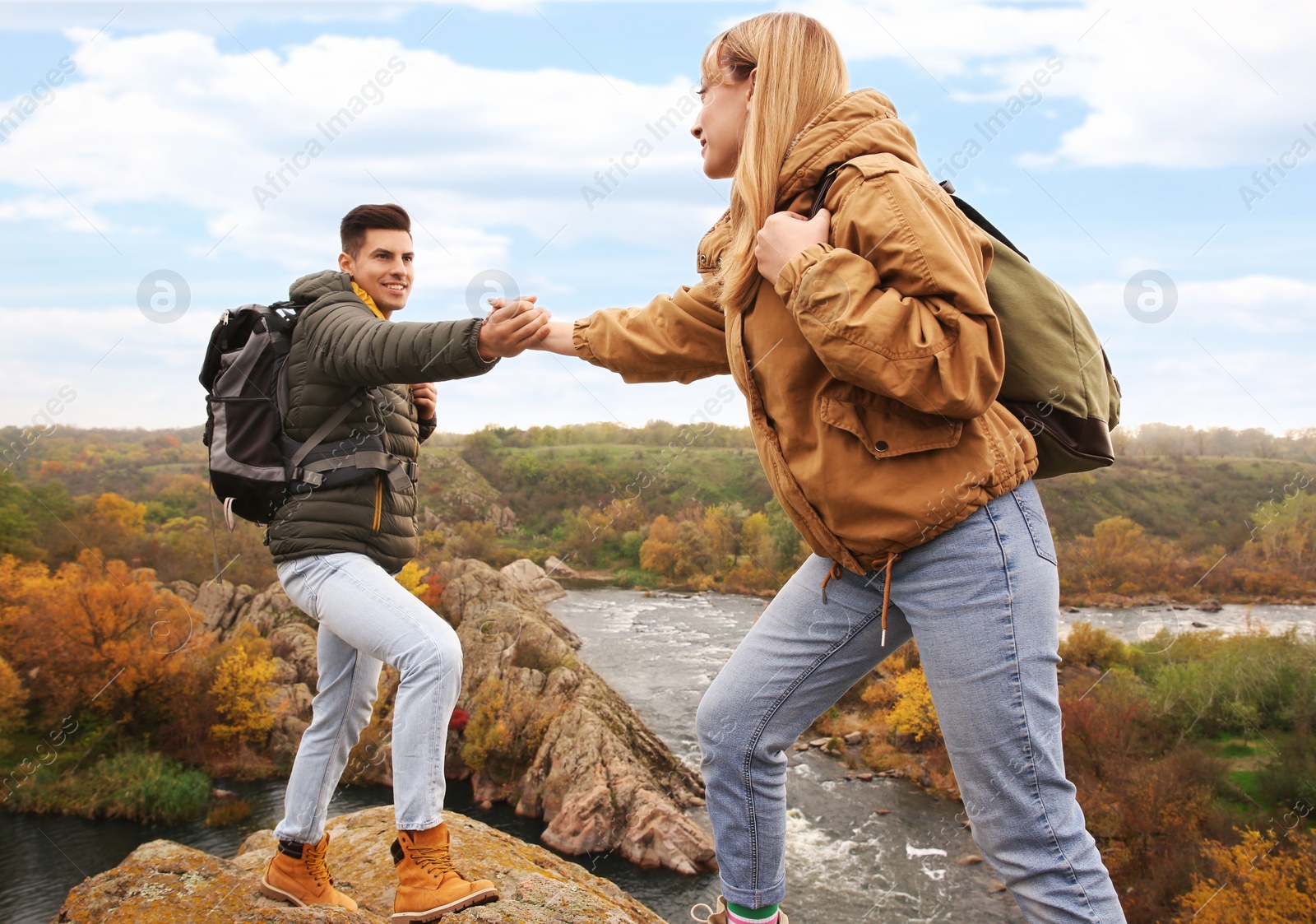 Photo of Couple of hikers with backpacks climbing up mountains