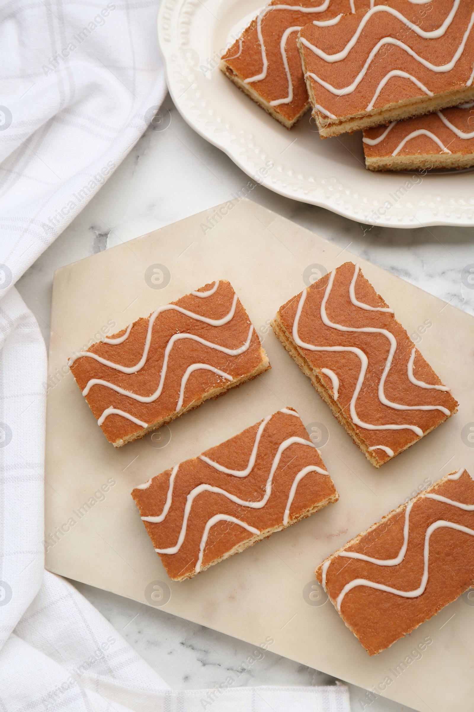 Photo of Tasty sponge cakes on white marble table, flat lay