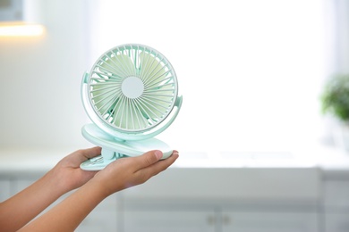 Closeup view of little child with portable fan on blurred background, space for text. Summer heat