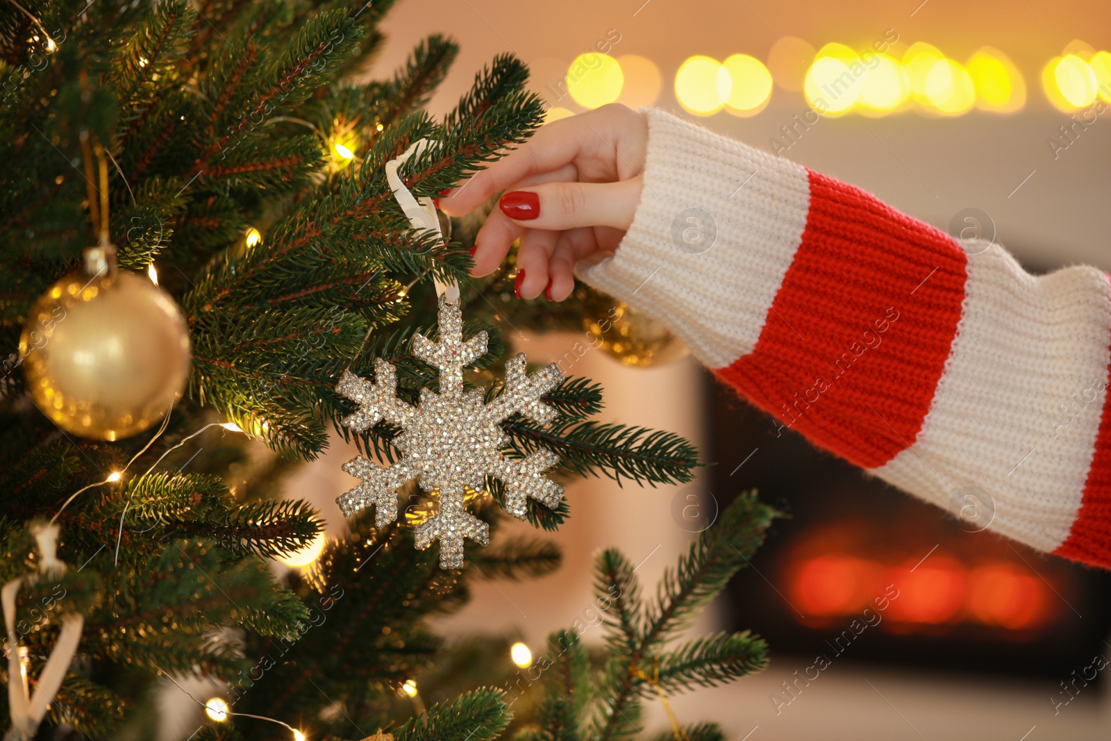 Photo of Woman decorating Christmas tree at home, closeup