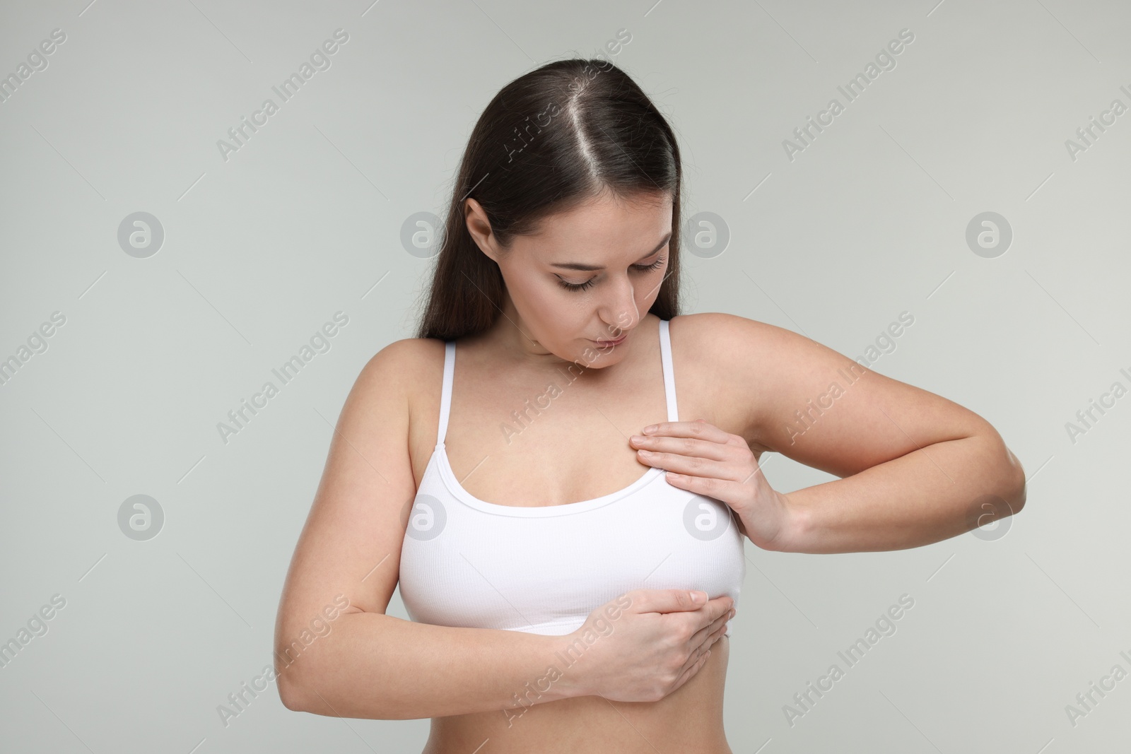 Photo of Mammology. Woman doing breast self-examination on light grey background