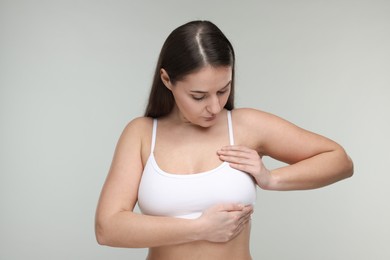 Mammology. Woman doing breast self-examination on light grey background