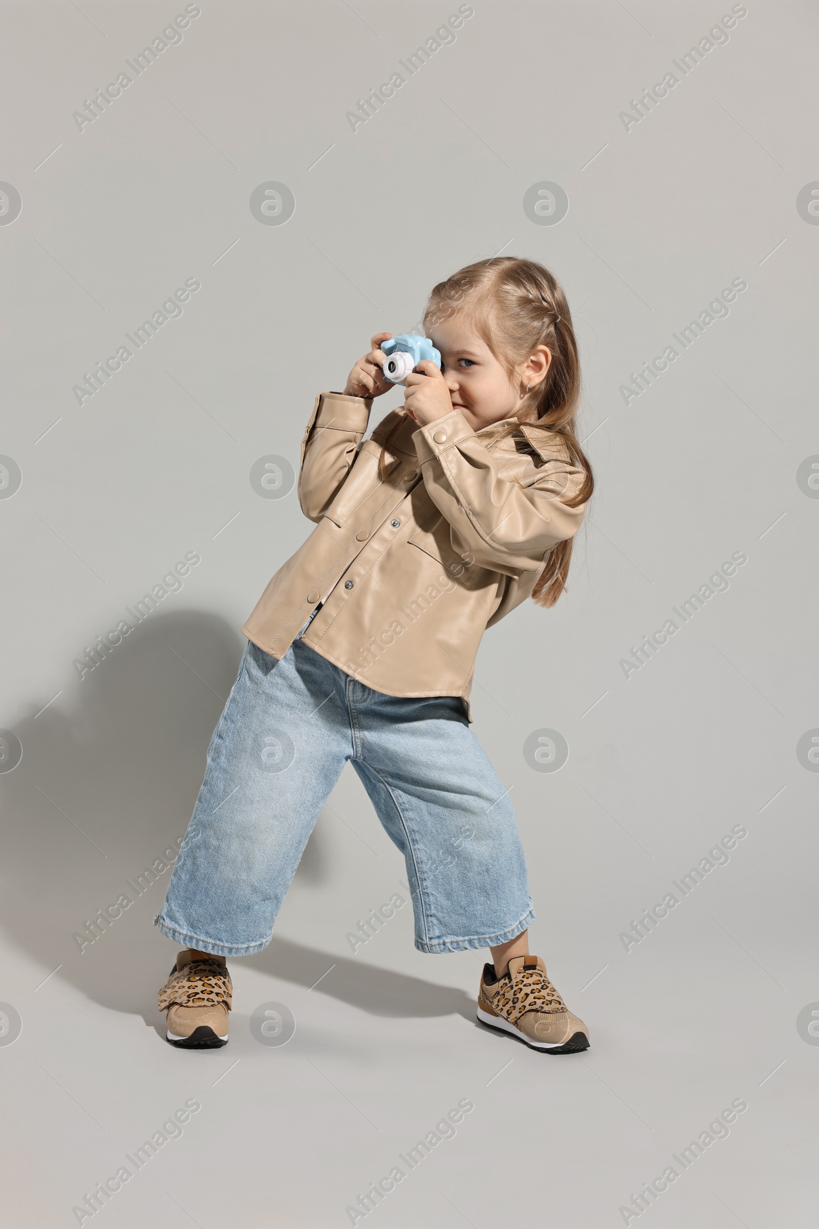 Photo of Fashion concept. Stylish girl with toy camera on light grey background