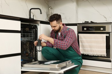 Photo of Repairman holding drain filter near dishwasher in kitchen