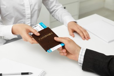 Manager giving passport and ticket to man at desk in travel agency office, closeup