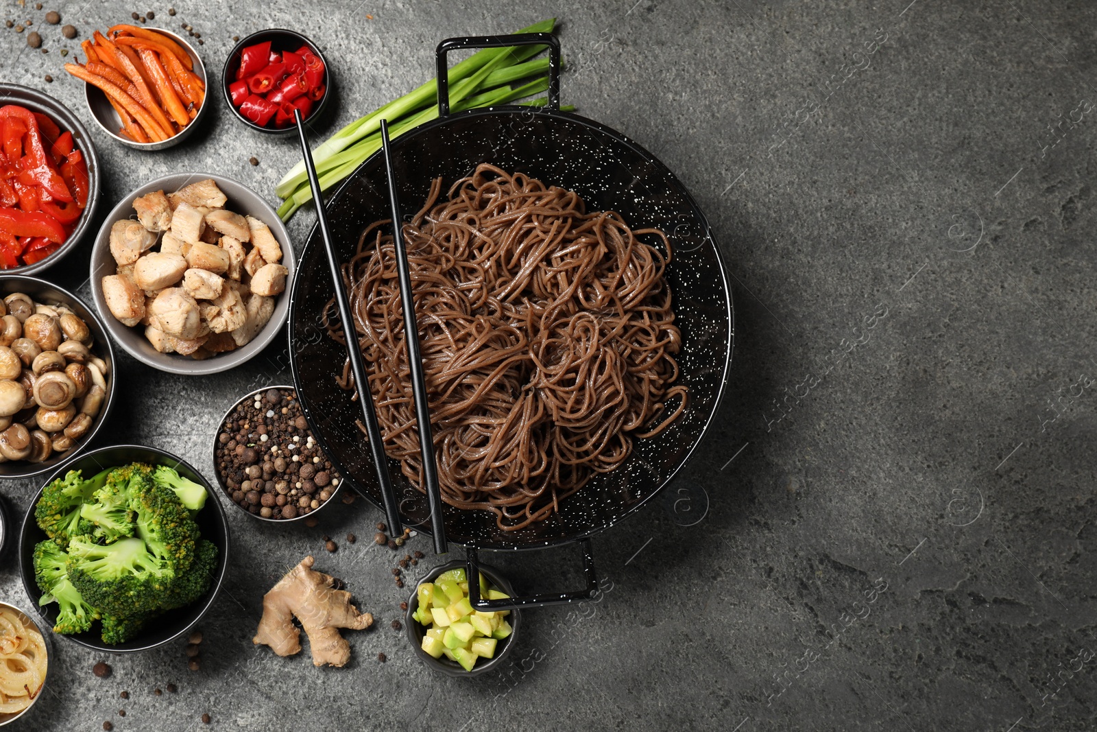 Photo of Wok with noodles, chicken and other products on grey table, flat lay. Space for text