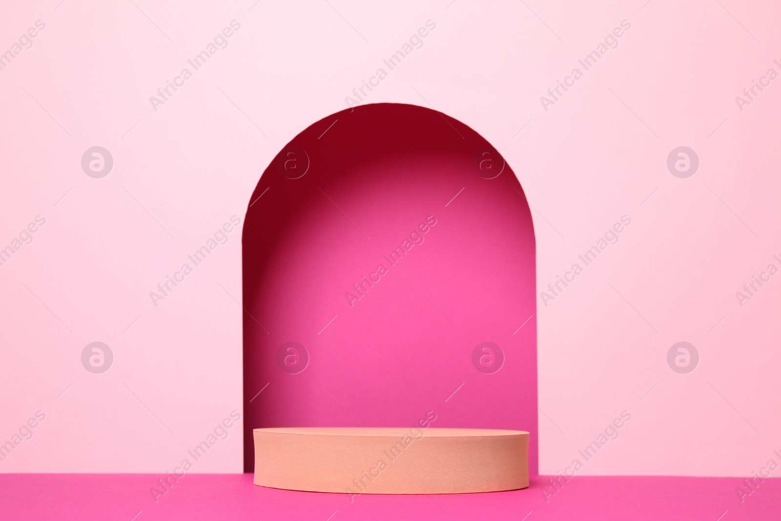 Photo of Orange geometric stand on pink background. Stylish presentation for product