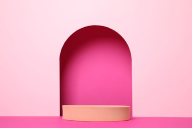 Photo of Orange geometric stand on pink background. Stylish presentation for product
