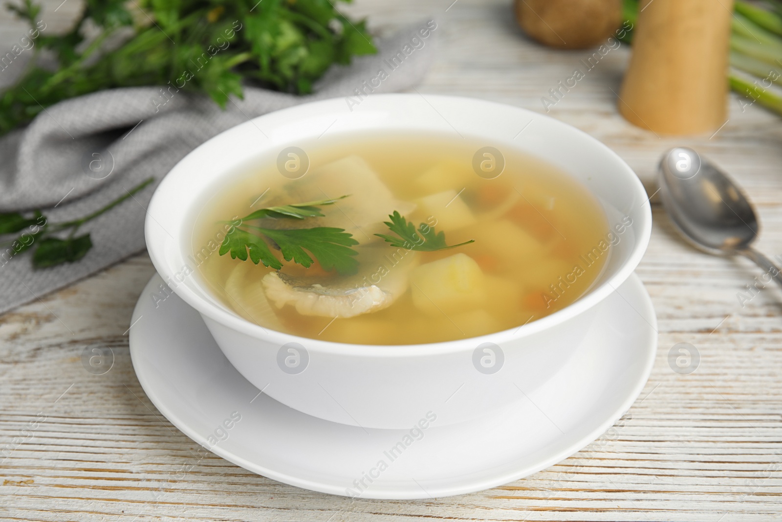Photo of Delicious fish soup in bowl on white wooden table