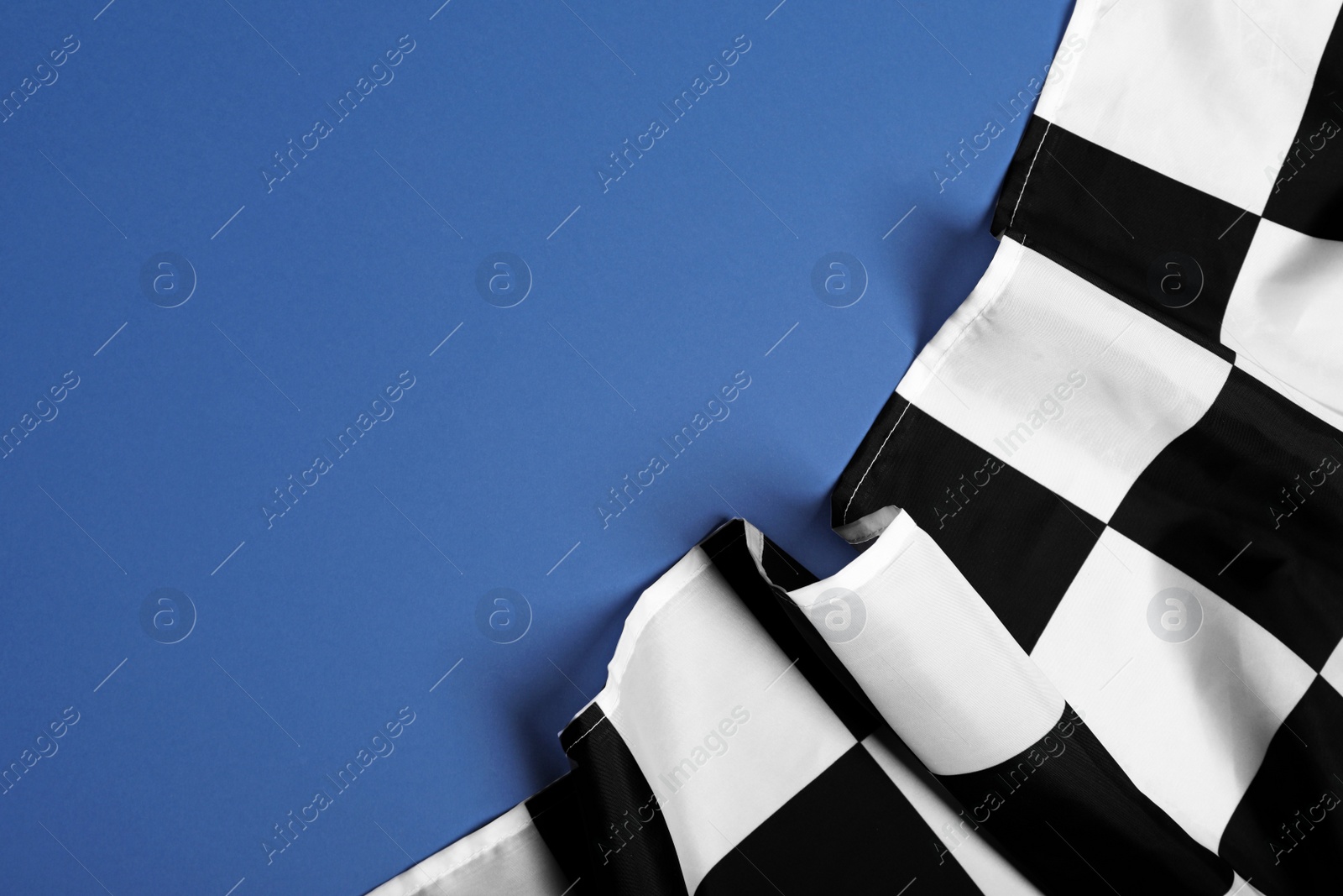 Photo of Checkered finish flag on blue background, top view. Space for text