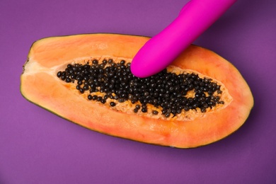 Half of papaya and vibrator on purple background, top view. Sex concept