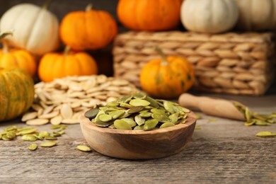 Photo of Bowl with pumpkin seeds on wooden table