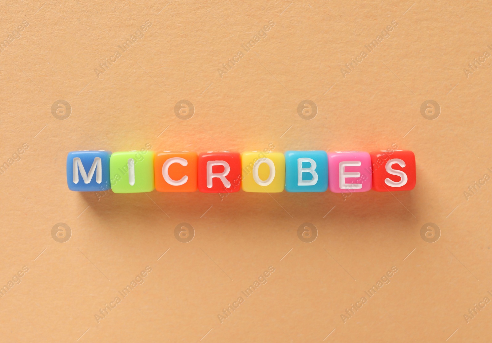 Photo of Word Microbes made with colorful cubes on color background, flat lay