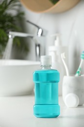 Mouthwash, toothbrushes and dental floss on white countertop in bathroom