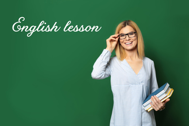 Image of Beautiful English teacher with books near chalkboard