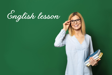 Beautiful English teacher with books near chalkboard