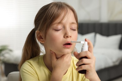 Photo of Little girl using throat spray at home
