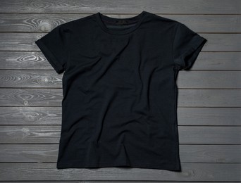 Stylish black T-shirt on gray wooden table, top view