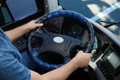 Photo of Professional bus driver at steering wheel. Passenger transportation