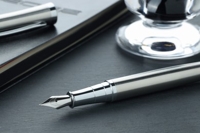 Photo of Stylish fountain pen and notebook on grey textured table, closeup