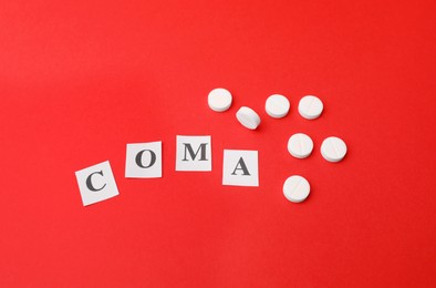 Word Coma made of letters and pills on red background, above view