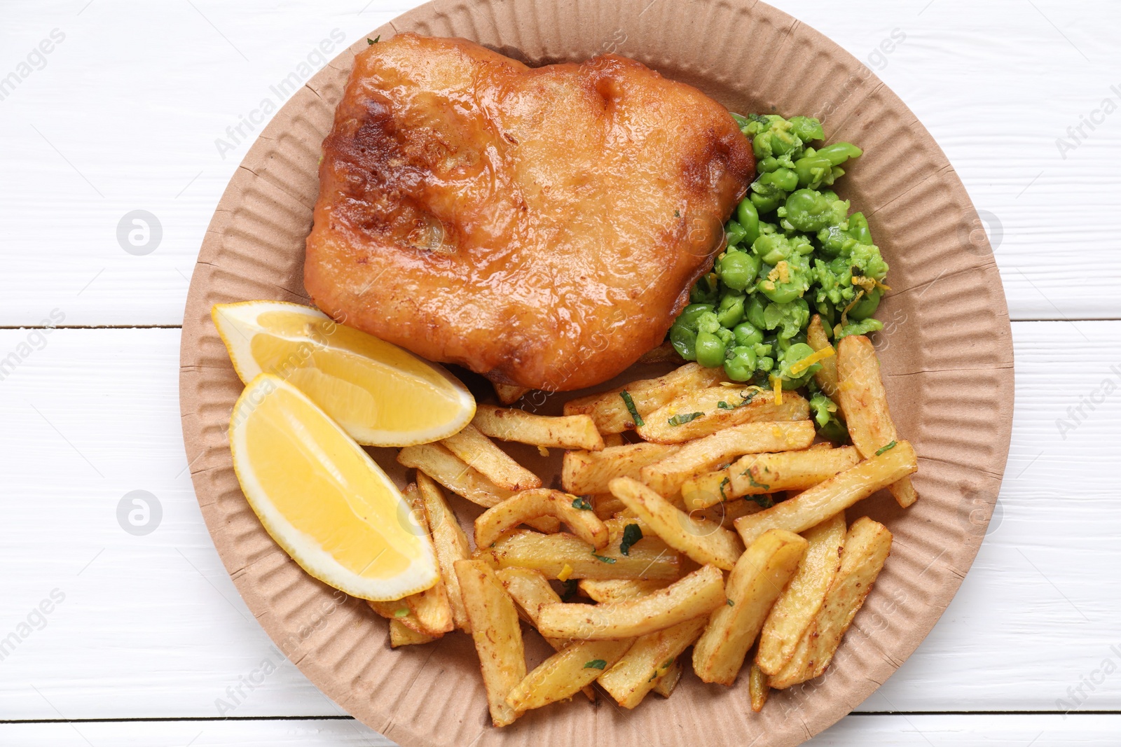 Photo of Tasty fish, chips, peas and lemon on white wooden table, top view