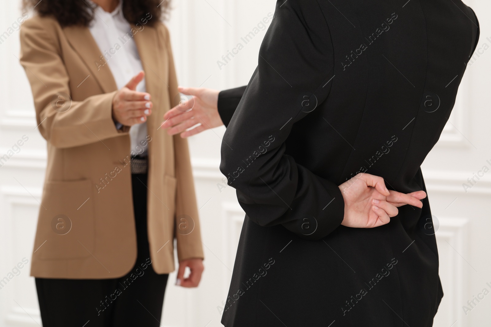 Photo of Employee crossing fingers behind her back while meeting with boss in office, closeup